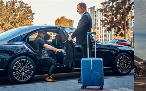 profesionalus vairuotojas pasitinkantis klientą prie prabangaus automobilio