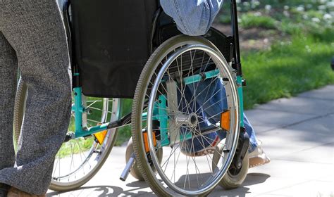 Teminė nuotrauka: dviratininkas, žmogus neįgaliojo vežimėlyje ir asmuo su elektriniu paspirtuku eina saugiai per miestą