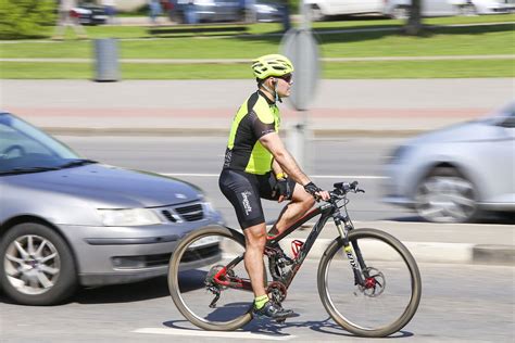Dviratininkas su šalmu ir liemene, rodantis rankos signalą posūkiui