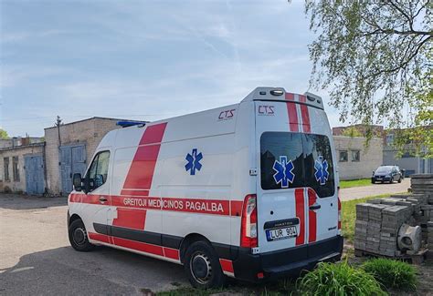 Policijos ir greitosios pagalbos ekipažai prie avarijos vietos su motociklu ir automobiliu