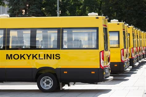 Geltonas mokyklinis autobusas su išskleistu STOP ženklu ir mirgančiomis šviesomis