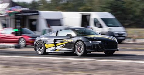 Dalyviai su galingais sportiniais automobiliais prie starto linijos drag lenktynėse.