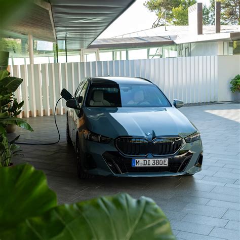Tematinė nuotrauka: vyras stovi prie savo BMW automobilio ir kalbasi su supirkimo įmonės atstovu, fone matomas tralas