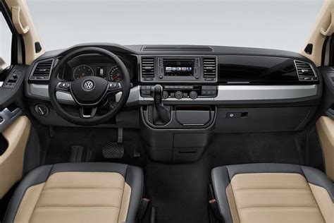Interior of the VW Caravelle, showing spacious seating, dashboard with large infotainment screen, and panoramic sunroof