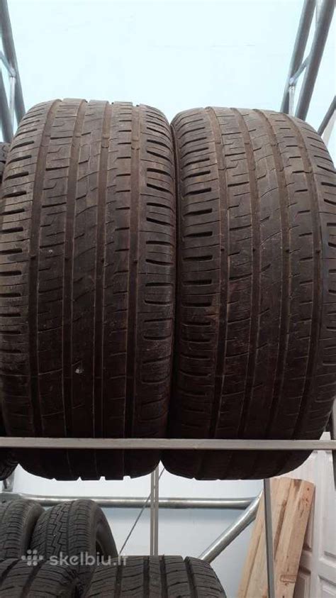Tematinė nuotrauka, vaizduojanti naudotas automobilių padangas, sukrautas sandėlyje Ukmergėje, su skirtingais dydžiais ir gamintojų ženklais
