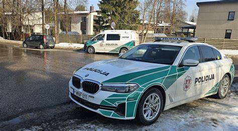 Teminė nuotrauka: policijos automobilis prie sustabdyto automobilio, šalia šviesoforo