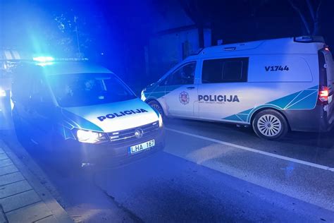 Policijos patrulio automobilis sustabdęs automobilį naktį prie kelio ženklo 