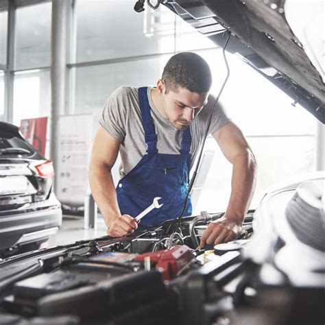 automobilių mechanikas dirba prie itališko automobilio variklio skyriaus, naudojant specializuotus įrankius