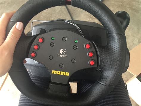 Logitech Momo Racing Wheel įrenginio nuotrauka, išryškinanti klasikinį dizainą ir sekvencinę pavarų svirtį.