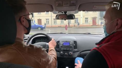 Teminė nuotrauka: žmogus, vairuojantis automobilį miesto gatvėje, su instruktoriaus pagalba