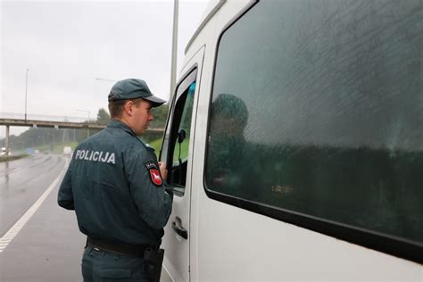 Policijos pareigūnai tikrinantys krovininio automobilio vairuotoją prie alkotesterio
