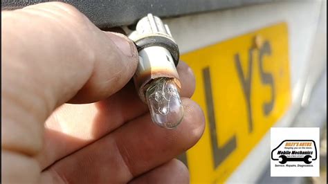 Close-up photo of inserting a new license plate bulb into its socket