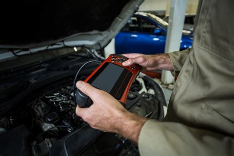 Tematinė nuotrauka: mechanikas, jungiantis kompiuterinės diagnostikos įrangą prie BMW automobilio