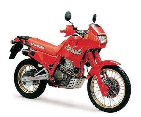 Honda NX 650 Dominator motociklas, stovintis ant bekelės kelio su dulkių fonu