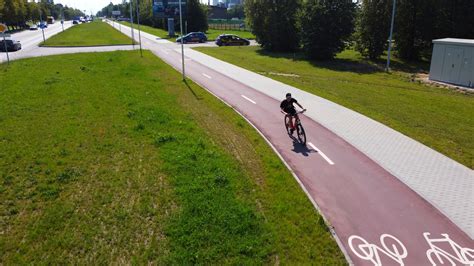 Iš arti nufotografuotas raudonos spalvos dviračių takas su ženklais Pramonės gatvėje.