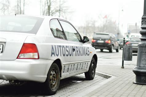 Teminis automobilis su ryškia įmonės reklama, važiuojantis miesto gatve