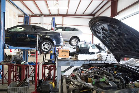 Nuotrauka, vaizduojanti modernų automobilių remonto servisą su įvairia įranga ir automobiliais