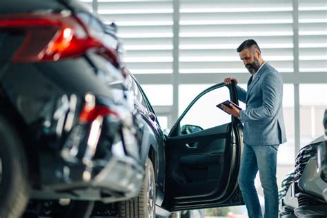Teminė nuotrauka: naudotas automobilis, atidžiai apžiūrimas pirkėjo ir pardavėjo, pabrėžiant patikros svarbą.