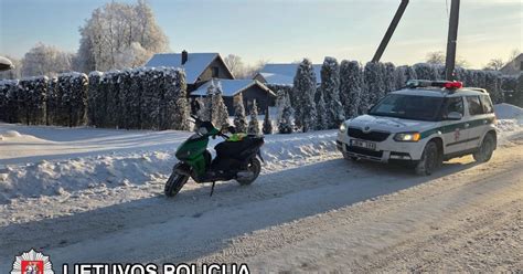 Teminė nuotrauka su motoroleriu ir motociklininku dėvinčiu šalmą mieste