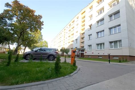 Daugiabučio namo kiemas su stovinčiais automobiliais, iliustruojantis automobilių parkavimo problemą.