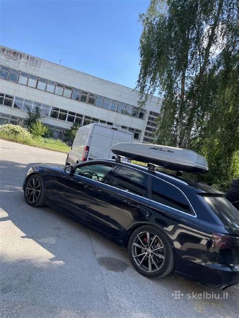 Kelioninis automobilis su pilnai pakrauta stogo bagažine ir dviračių laikikliu ant galo