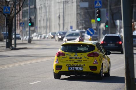 tematinė nuotrauka: besišypsantis mokinys ir vairavimo instruktorius prie automobilio