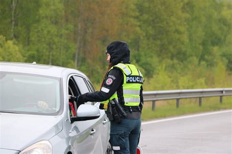 Eismo įvykio vieta Latvijoje su policijos pareigūnais ir sudužusiu automobiliu