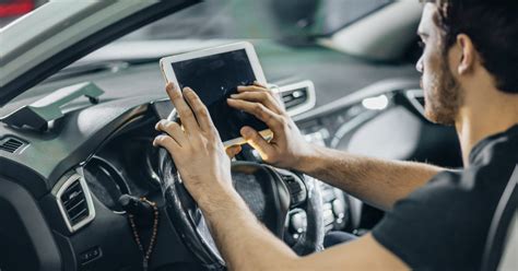 Automobilių serviso darbuotojas atlieka diagnostiką prie kompiuterio