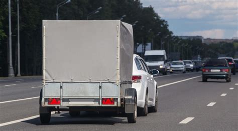 Tematinė nuotrauka: Automobilis su priekaba važiuojantis per lietų