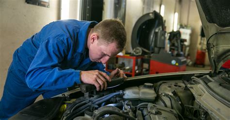 Nuotrauka, kurioje autoserviso meistrai dirba su Peugeot automobiliu