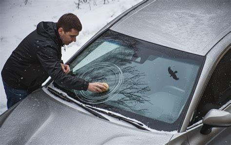 darbuotojas, keičiantis automobilio galinį stiklą, naudodamas specialius įrankius ir sandariklius