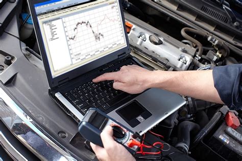 meistras atliekantis automobilio diagnostiką su kompiuteriu