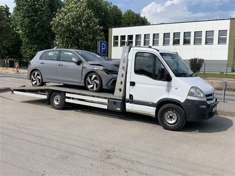 nuotrauka su vilkiku ir tralu, vežančiu automobilį