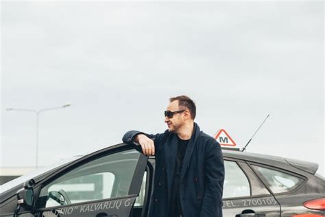 Foto su besišypsančiais keliautojais prie išsinuomoto automobilio