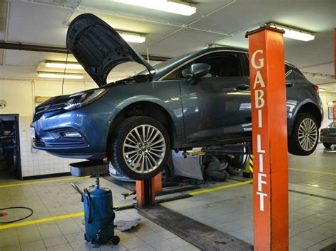 Autoserviso Pakruojyje interjeras su specialistu, dirbančiu prie automobilio variklio