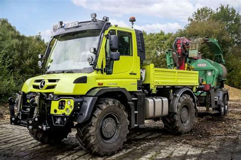 Mercedes-Benz Unimog U535 dirbantis lauke su prikabintu skutikliu, demonstruojantis universalumą žemės ūkyje
