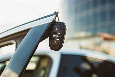 Teminė nuotrauka: besišypsantis žmogus prie modernaus automobilio su rakteliais rankoje