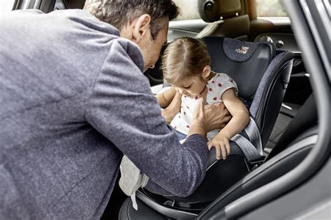 Tėvai tvirtina automobilinę kėdutę su kūdikiu į automobilį
