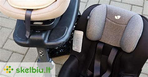 Tėvai apžiūri automobilinės kėdutės etiketę su saugumo standartų žymėjimu