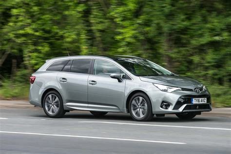 Iliustracija, vaizduojanti Toyota Avensis universalą su atidaryta bagažine.