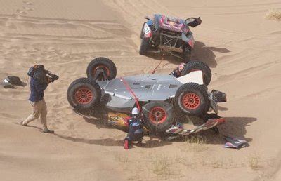 RC buggy šokinėja per smėlio kopą, pakėlęs dulkes