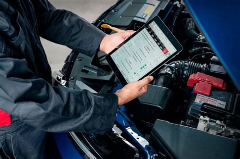 Mechanikas, atliekantis automobilio diagnostiką su kompiuteriu