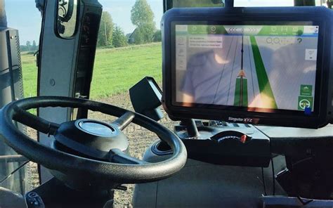 Nuotrauka, vaizduojanti traktoriaus kabiną su įrengtu automatinio vairavimo sistemos monitoriumi.
