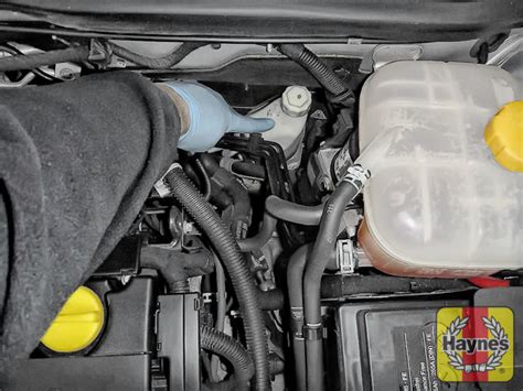 The power steering fluid reservoir in an Opel Astra H engine bay