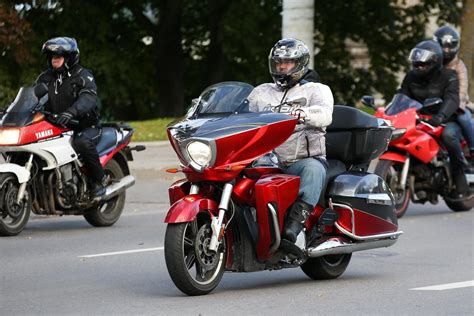 Motociklininkas su motoroleriu važiuoja keliu tarp miestų