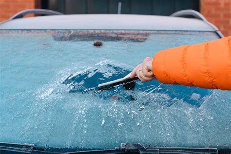 Teminė nuotrauka: žmogus, įsitvėręs vairo, matomas per priekinį automobilio stiklą mieste