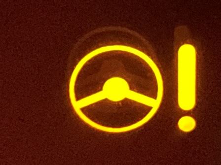Thematic photo of a car dashboard with a steering wheel and a warning light