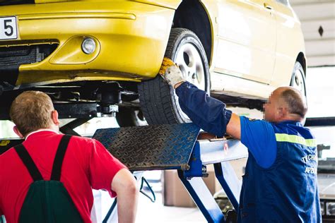 Techninės apžiūros specialistas tikrina automobilio važiuoklę ant keltuvo