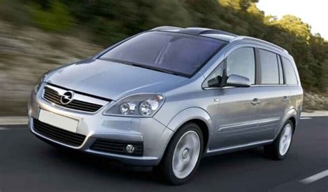„Opel Zafira“ veidrodėlio nuėmimo proceso schema, rodanti, kaip plastikiniu įrankiu atkabinti seną stiklą ir atjungti šildymo laidus.
