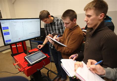 Nuotrauka, vaizduojanti studentus praktiniuose užsiėmimuose automobilių elektronikos dirbtuvėse